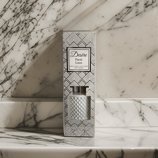 A Fresh Linen Reed Diffuser from The Soap Gal x, labeled "desire fresh," displayed on a marble surface with a geometric pattern on the packaging.