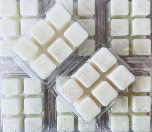 Overhead view of packaged square mochi desserts in uniform arrangement with A Cup Of Warmth Wax Melt fragrance by The Soap Gal x.