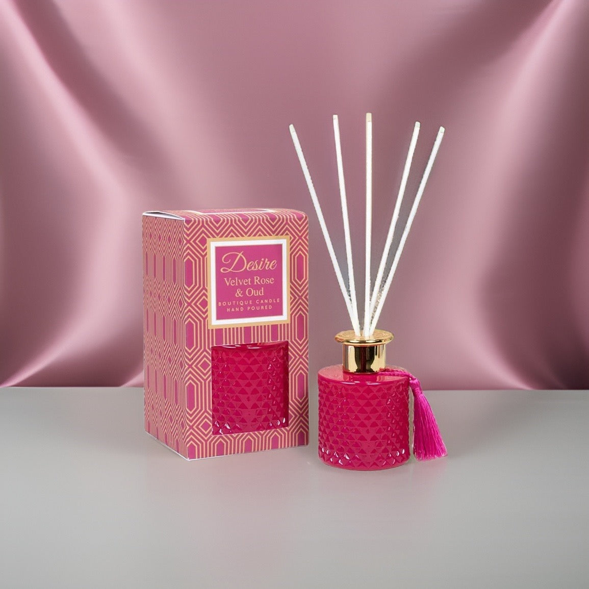 A Velvet Rose And Oud reed diffuser by The Soap Gal x on a pink background.