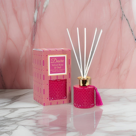 A pink The Soap Gal x Velvet Rose and Oud reed diffuser on a marble table.
