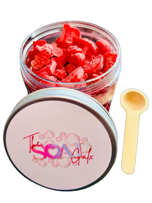 A jar of red The Soap Gal x Wax Melt Scoopies with a wooden spoon on a black background.