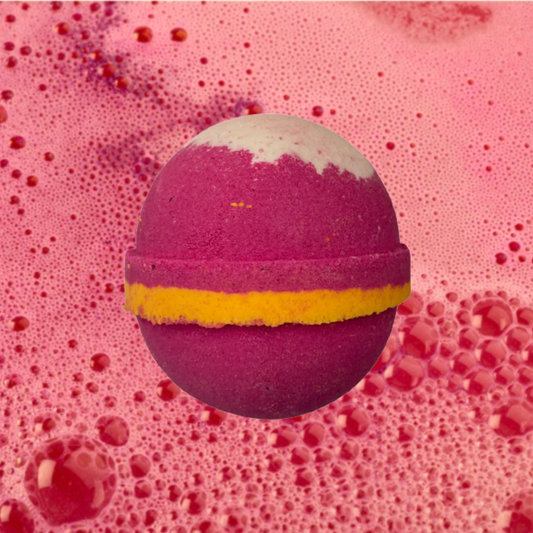 A colorful Cherry Bakewell Bath Bomb with a yellow stripe on an effervescent pink background by The Soap Gals.