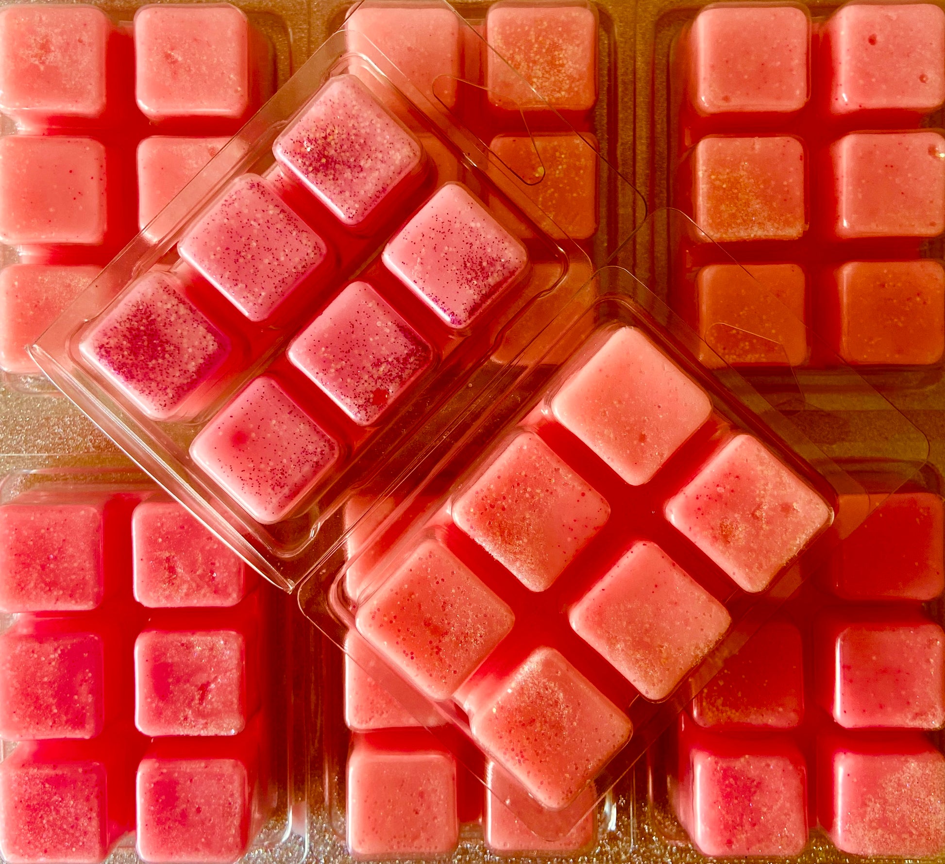 Trays of Spiced Blackberry Jam wax melts from The Soap Gal x, sprinkled with glitter, stacked and arranged neatly, casting soft light reflections.