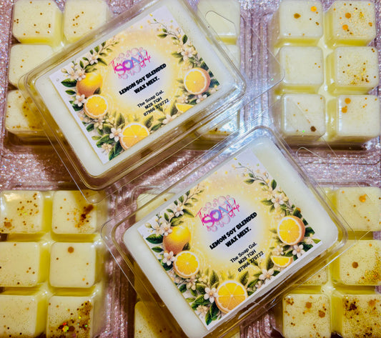 Two containers of The Soap Gal x Lemon and Meringue Pie Wax Melts displayed on a sparkly pink background, each labeled with ingredients and a floral and citrus design.