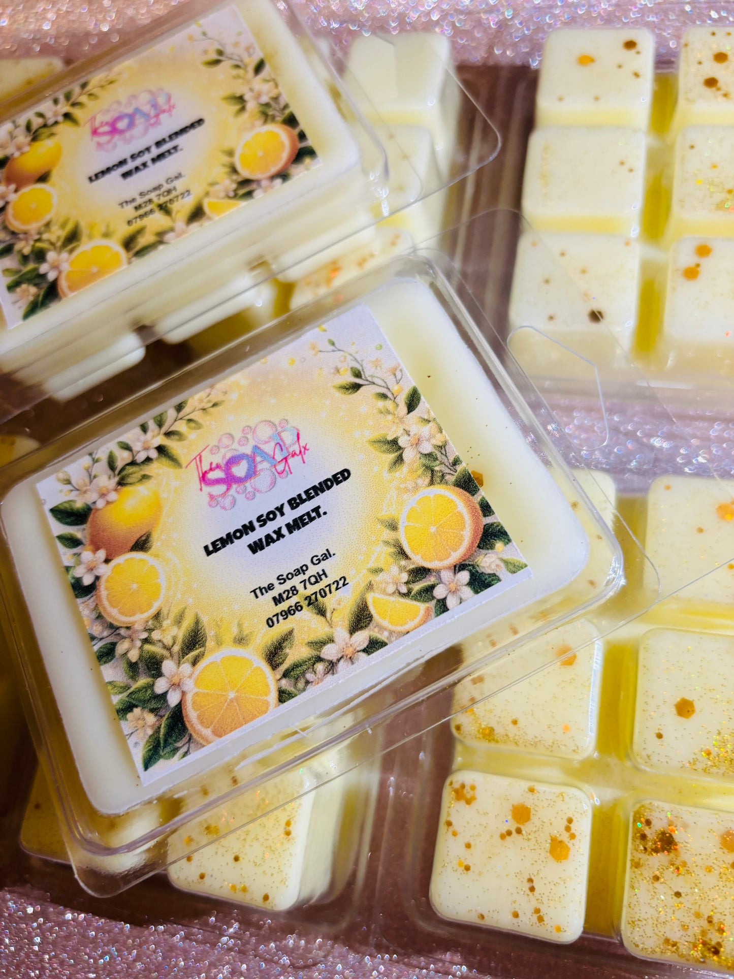 Packaged Lemon and Meringue Pie Wax Melts by The Soap Gal x displayed on a sparkly pink background, some melts are visible outside the container, showcasing yellow color with speckles.