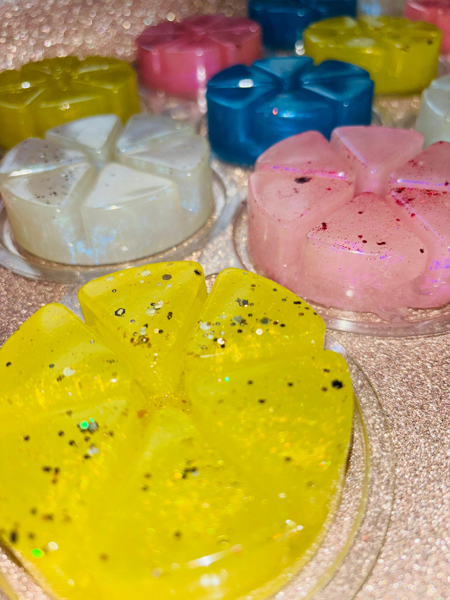 Colorful resin art pieces with glitter, displayed on a glittery surface, featuring various shapes and vibrant hues of highly scented The Soap Gal x Gel Wax Melts 100g / Jelly Wax Melts 100g fragrances.