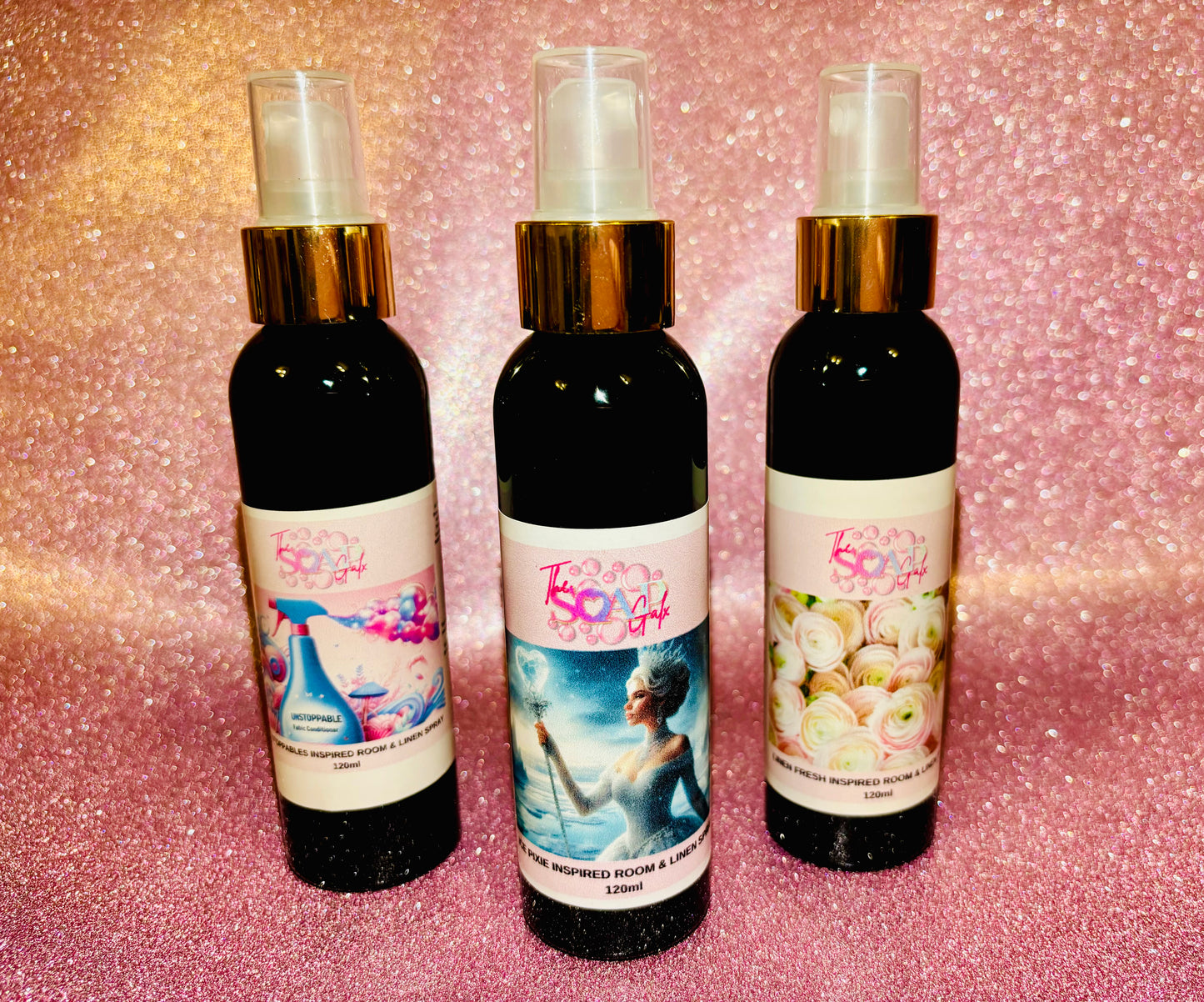 Three bottles of Inspired Room Sprays with different scents on a sparkly pink background from The Soap Gals.