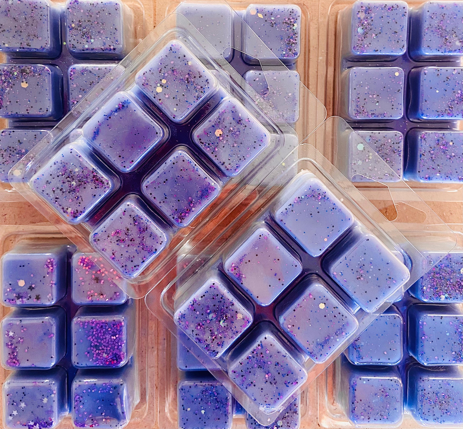 Several packs of Aliens Wax Melts infused with fragrance oils, arranged in a grid pattern by The Soap Gals.