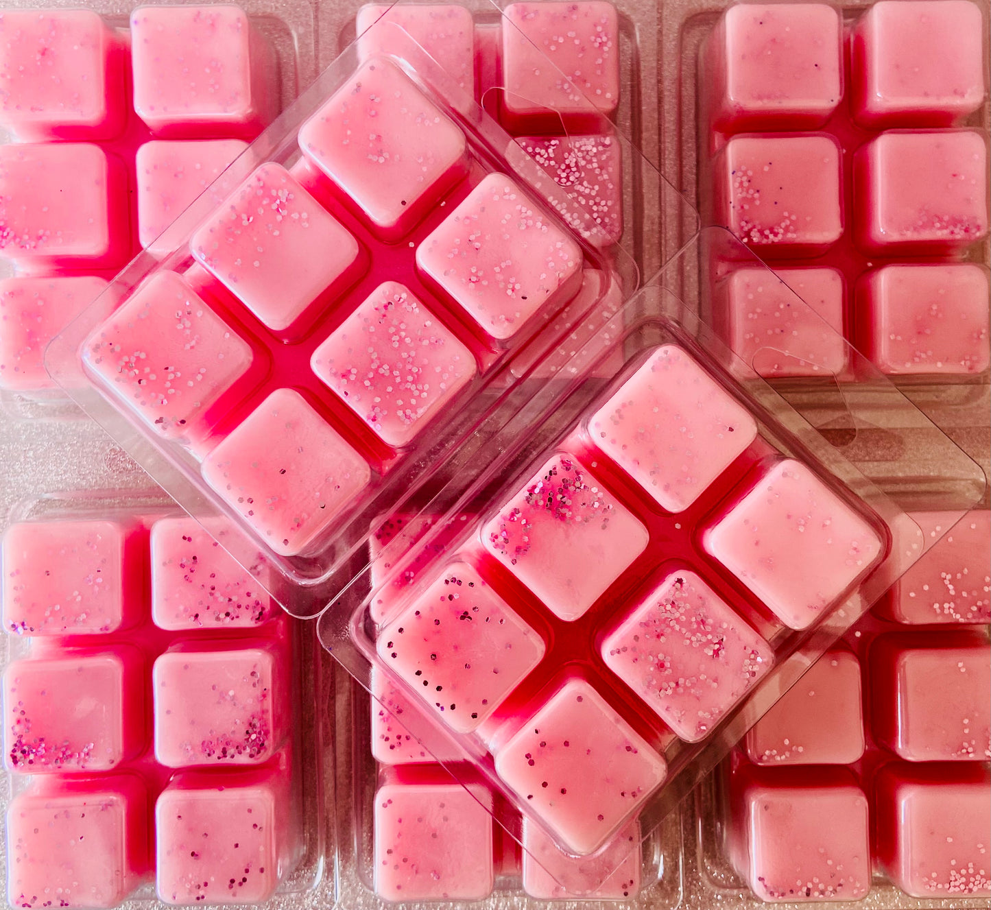 A bunch of pink squares in a plastic container, perfect for Toasted Marshmallow Wax Melts by The Soap Gals.