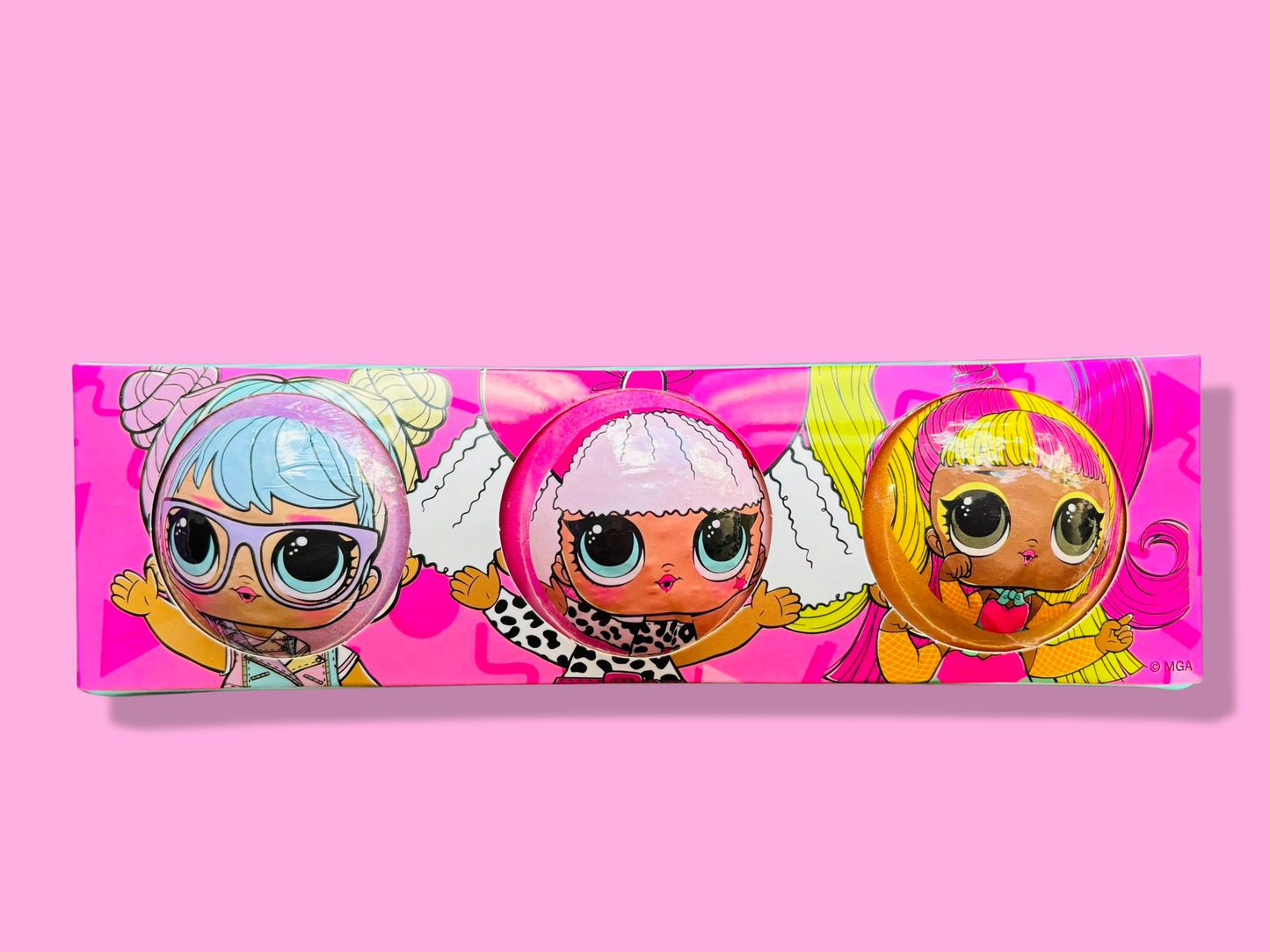 Three cartoon characters with large eyes and colorful costumes are displayed on a pink rectangular package, making it the perfect gift for little girls who love The Soap Gal x LOL Dolls Bath Bombs 3 Pack. Enjoy a fragrant bath experience with these delightful surprises inside!