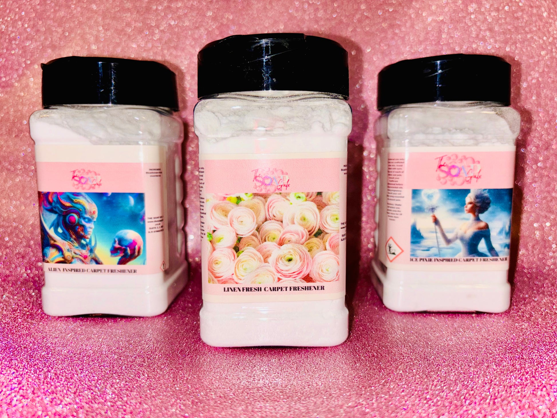 Three jars of The Soap Gals Scent and Vac Laundry & Perfume Fragrance Carpet Freshener powder on a pink background.