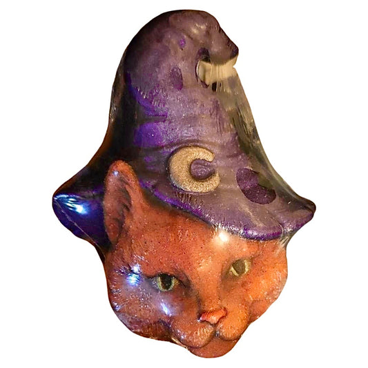 A decorative The Cheshire Cat Bath Bomb with a whimsical purple hat by The Soap Gal x.