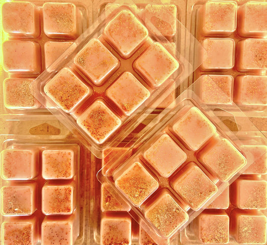 Multiple packs of square-shaped, orange-hued Bum Bum Cream Wax Melts with glitter sprinkled on top by The Soap Gals.