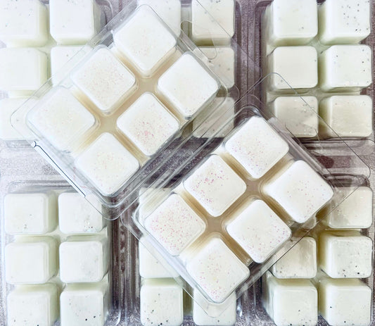 Packages of uniform square-shaped dessert items, potentially mochi or confections, in clear plastic trays infused with The Soap Gal x Amethyst Crystal and Amber Wax Melt scented fragrance oils.