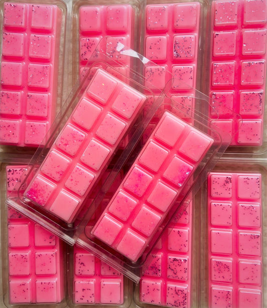 Several pink Lost in Cherry: Missing Cherry Wax Melt fragrance wax melts arranged in rows, some in plastic packaging from The Soap Gal x.
