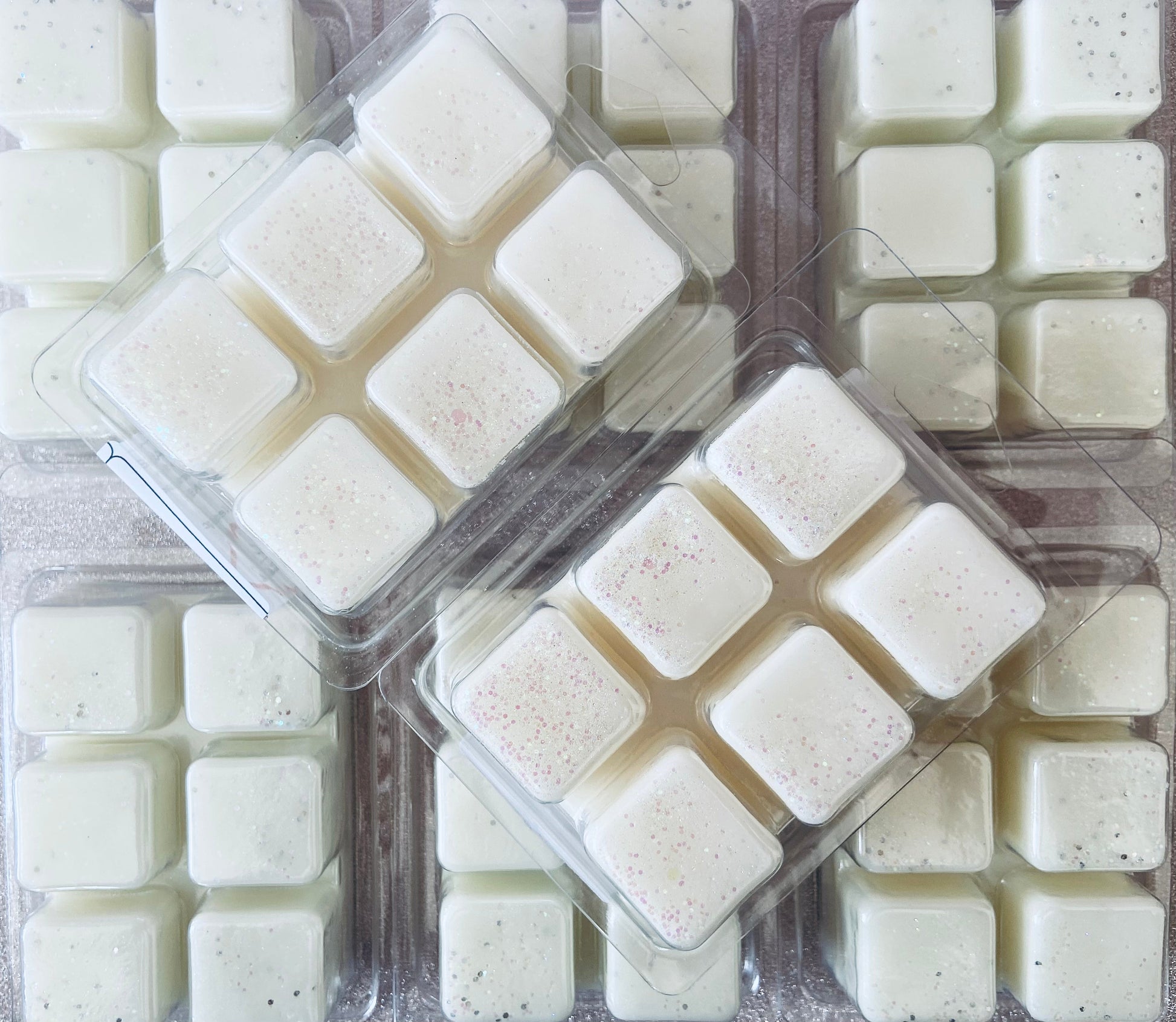 Trays of square-shaped, white Unstoppables Wax Melt candles with a sprinkling of pink speckles by The Soap Gals.