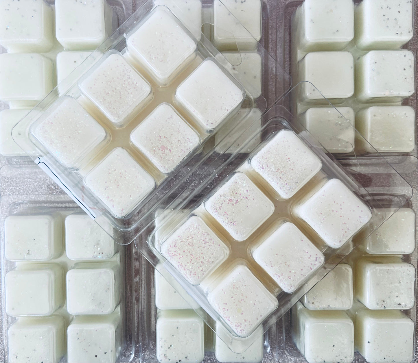 Multiple packages of high-quality, square-shaped Clean Cotton wax melts arranged neatly, some with speckles by The Soap Gals.