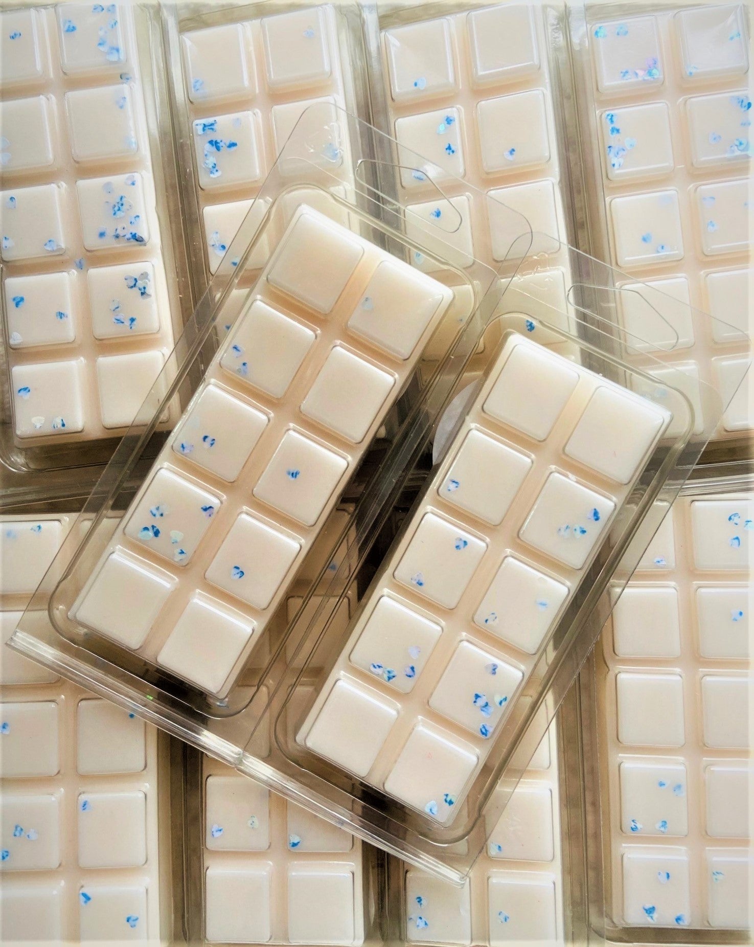 Multiple trays of white chocolate bars with blue sprinkles, packaged in clear plastic, now feature The Soap Gals Tranquil Sleep Wax Melts.