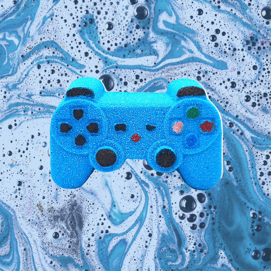 A blue Controller Bath Bomb from The Soap Gals covered with water droplets on a marbled blue and black background.