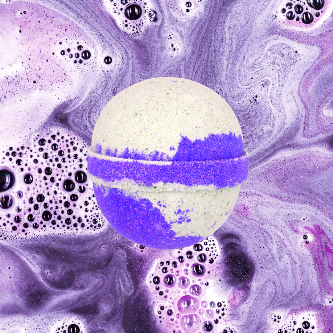A The Soap Gals Parma Violet Bath Bomb floating amidst a purple-hued foamy mixture, likely dissolving in water.