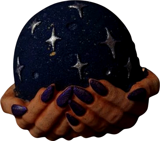 A person's hands with purple nail polish holding The Soap Gal x's The Witches Globe Bath Bomb, a dark, hand-painted globe with celestial themes.